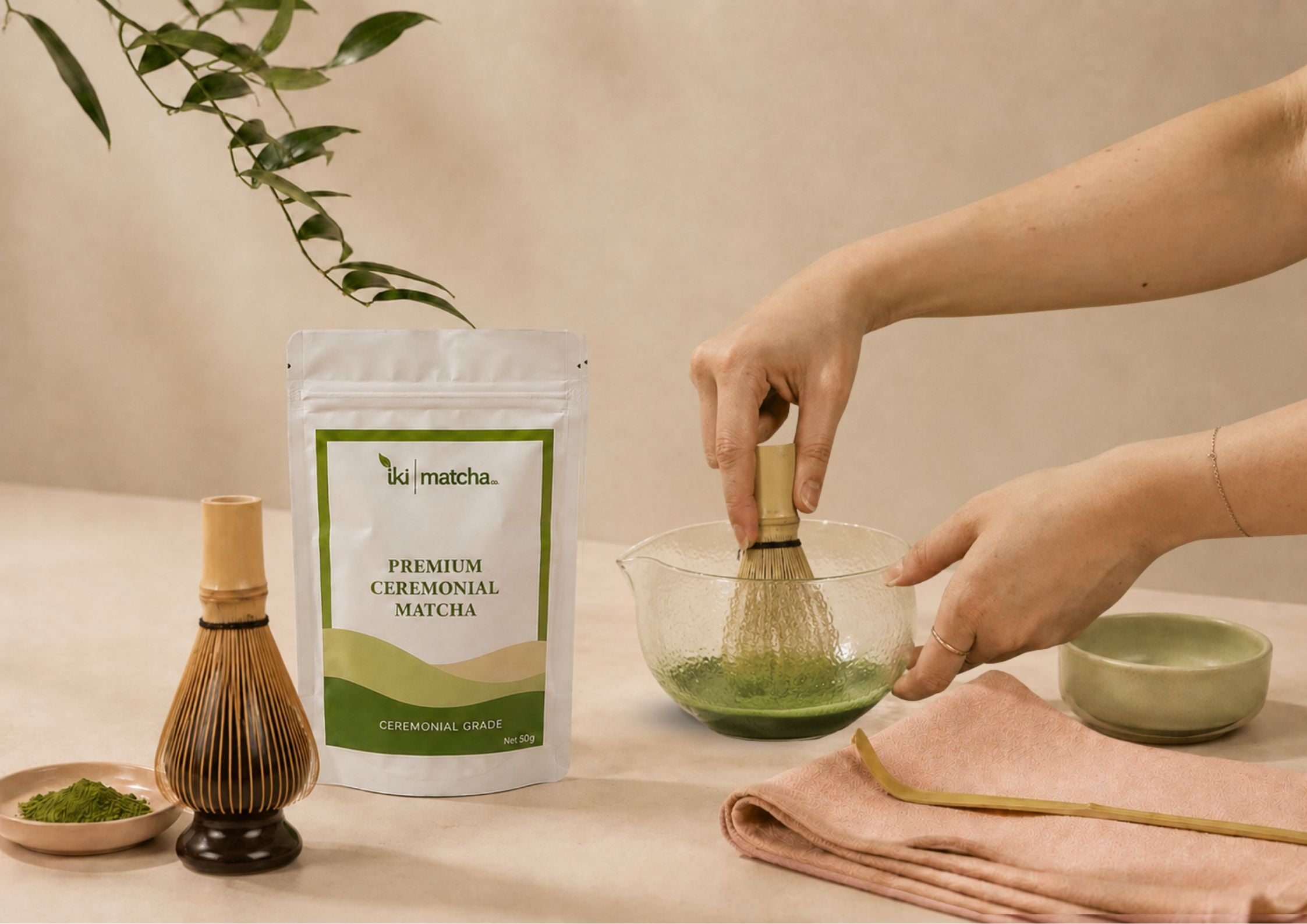 Person preparing matcha with a whisk and bowl on a beige background