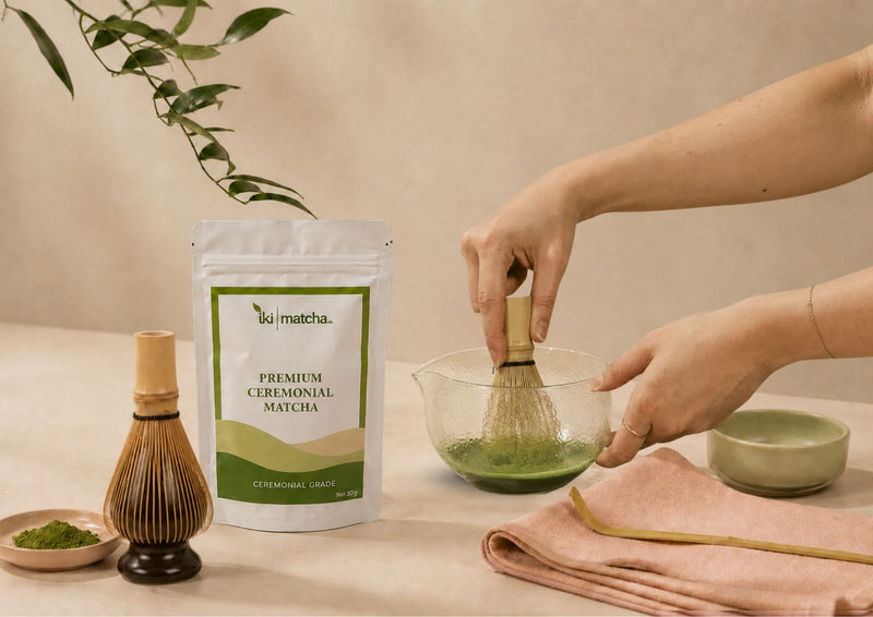 Person preparing matcha with a whisk and bowl on a beige background