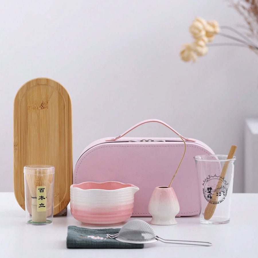 Pink travel tea set with accessories on a white surface
