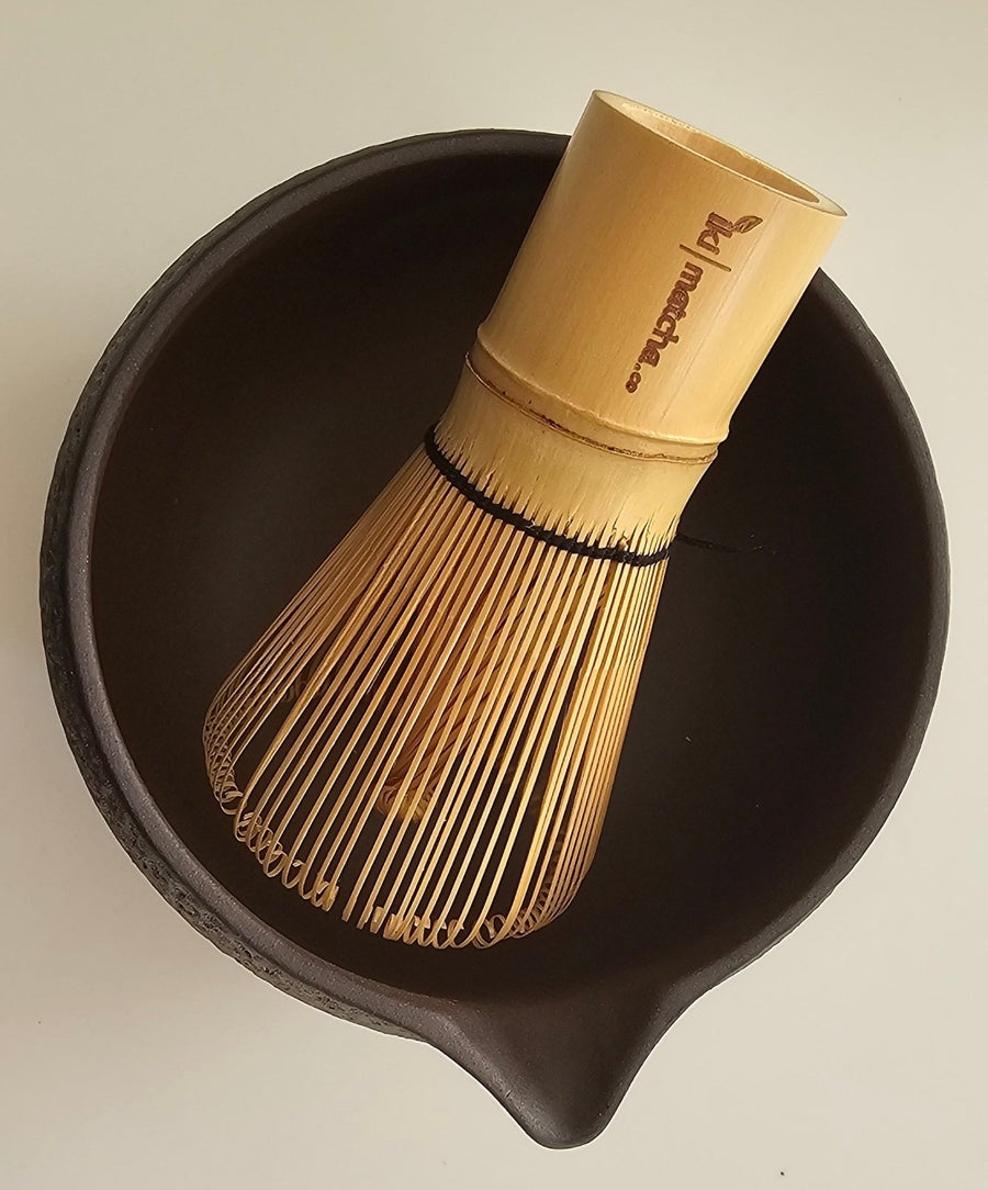 Bamboo whisk and black bowl on a beige background